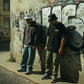 Dois homens usam Bucket Hat UNIFORM 00 da astredik, um branco e outro preto, em ambiente urbano com graffiti.