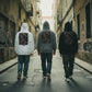 Três homens de costas vestindo hoodies astredik com estampa de coelho vermelho em beco urbano com graffiti